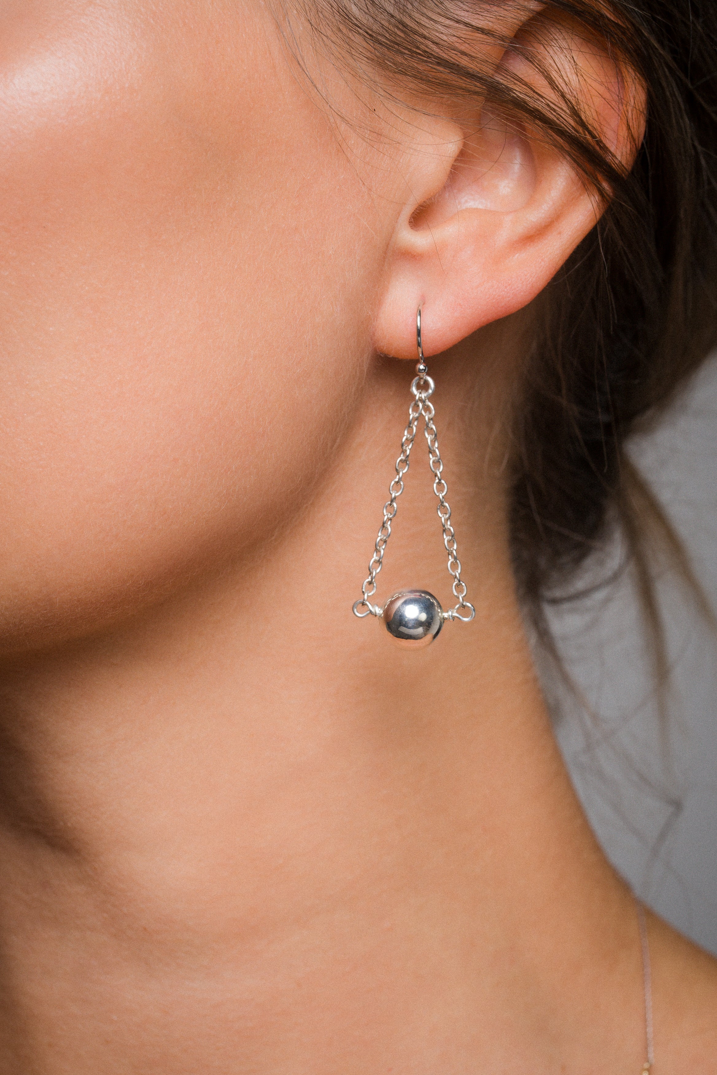 Close-up of AEJL Chandelier Orb Earring worn on ear, sterling silver sphere drop earring handcrafted in Sydney