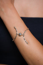 Load image into Gallery viewer, Silver bracelet with a central bead on a person's wrist against a dark background
