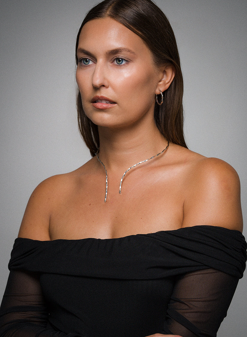 Woman wearing AEJL illusion necklet with black off-shoulder top with a gray background