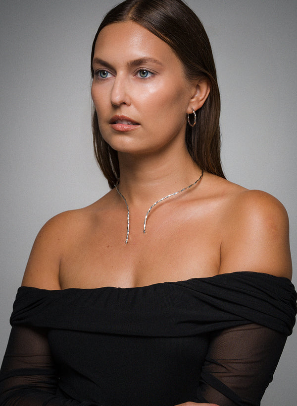 Woman wearing AEJL illusion necklet with black off-shoulder top with a gray background