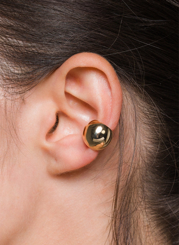 Close-up of an ear wearing a gold sphere ear cuff.