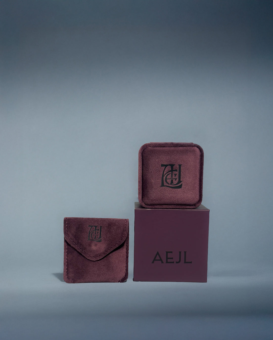 Plum velvet jewellery box set with 'AEJL' branding on a grey background
