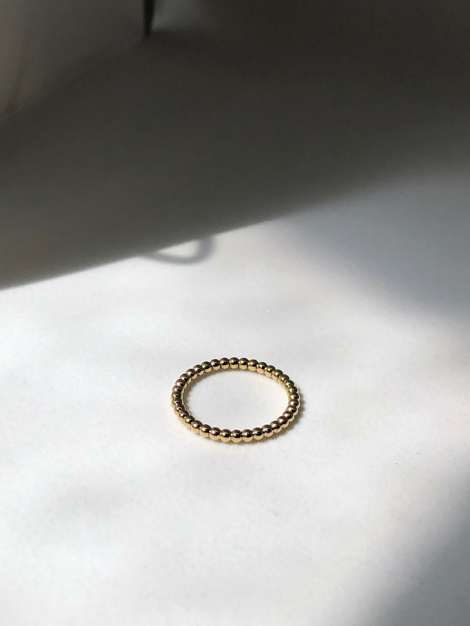 Dewdrop ring handmade in 9kt gold on a white surface 