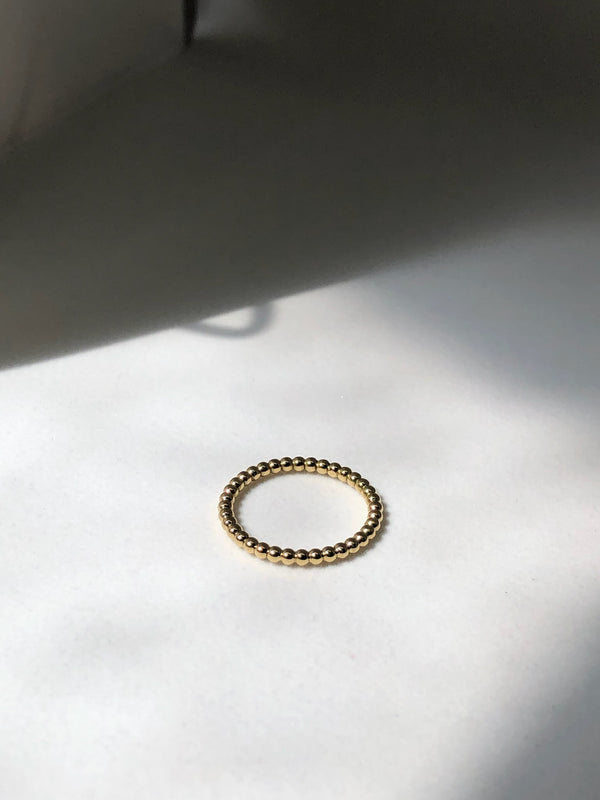Dewdrop ring handmade in 9kt gold on a white surface 